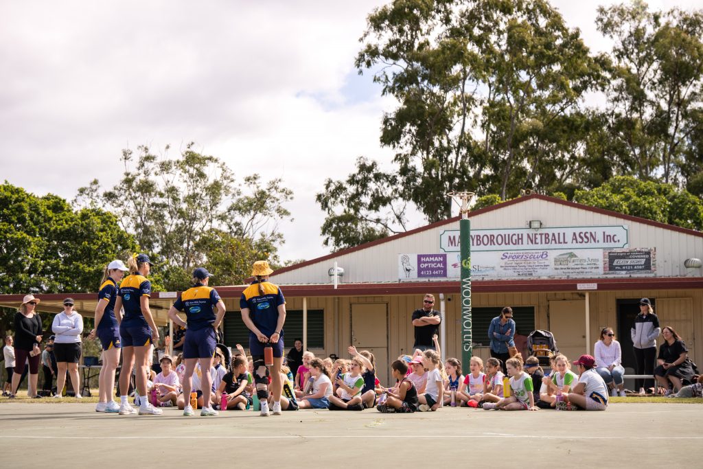 Sunshine Coast Lightning players Tara Hinchliffe, Reilley Batcheldor, Laura Scherian and Mahalia Cassidy stand in front of a group of kids at Maryborough netball association. They are answering questions from the kids during a question and answer session. 